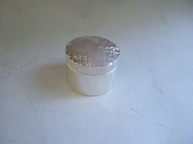 Appraisal: A silver cylindrical box and cover the top with a