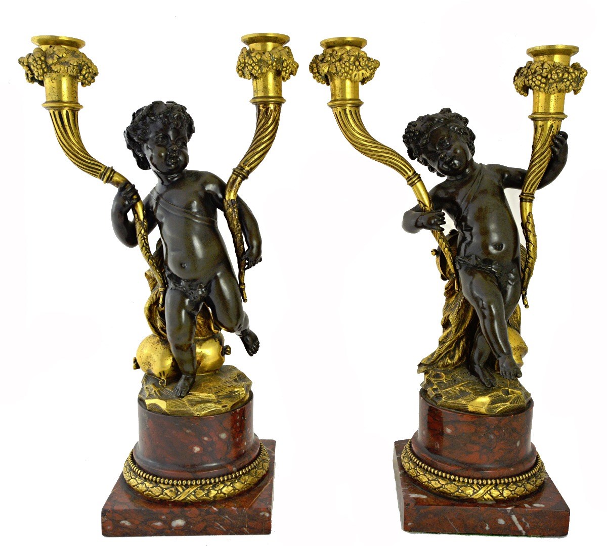 Appraisal: A pair of bronze and ormolu putto candlesticks on red