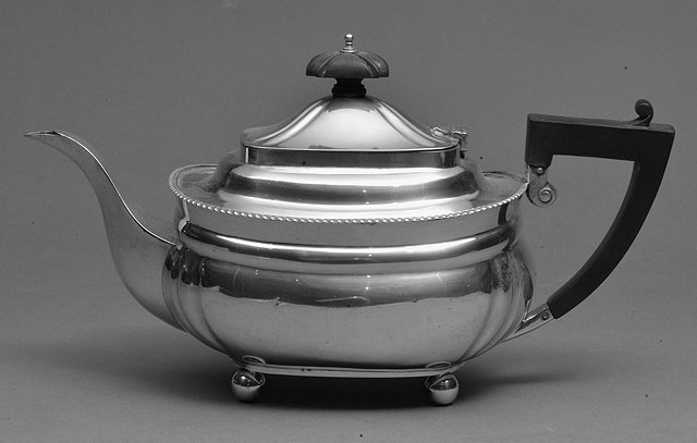 Appraisal: A GEORGIAN STYLE SILVER TEAPOT with gadrooned edge and hardwood