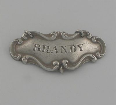 Appraisal: A Victorian curved wine label with scroll borders incised 'BRANDY'