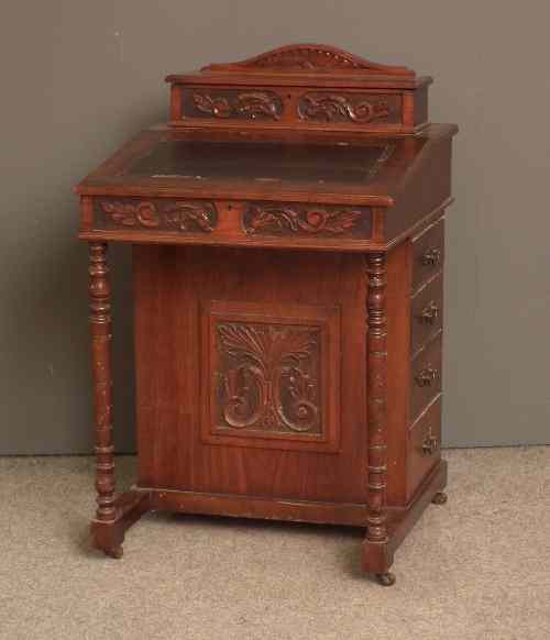 Appraisal: A late Victorian walnut Davenport with leaf carved front fitted