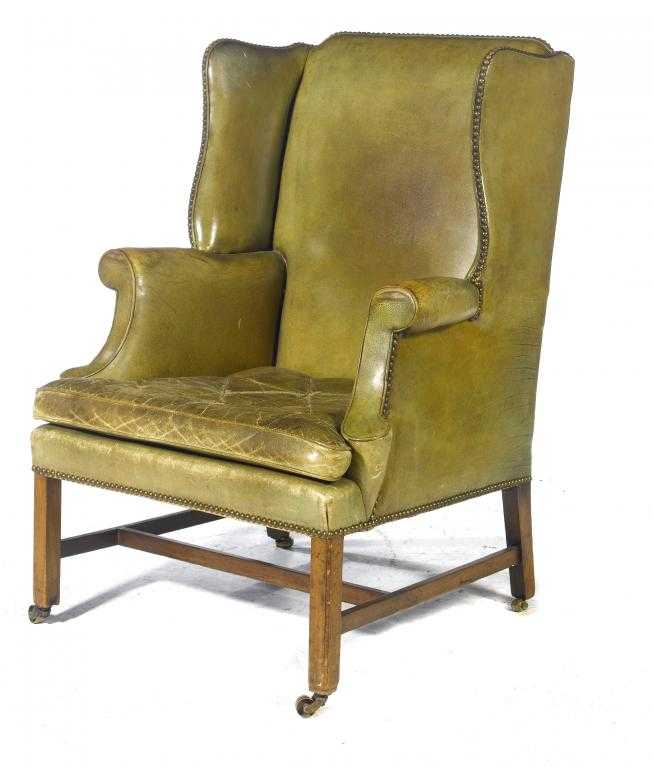 Appraisal: AN ARMCHAIR with shaped wing back and swept arms upholstered