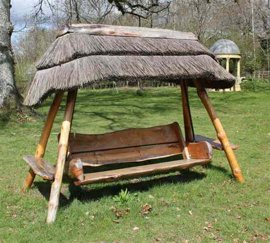 Appraisal: A naturalistic wood garden swing bench with thatched canopy Estimate