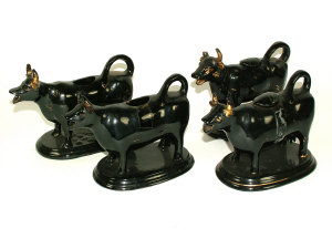 Appraisal: Four black glazed pottery cow creamers with gilt highlights the