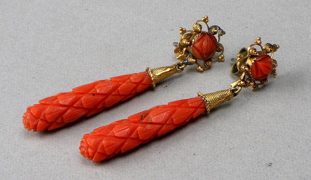 Appraisal: A PAIR OF CARVED CORAL DROP EARRINGS suspended from gilt