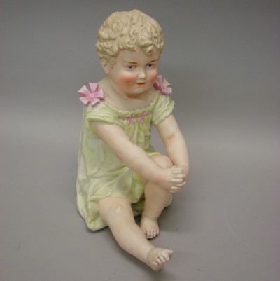 Appraisal: Unmarked sitting bisque piano baby Child is sitting holding a