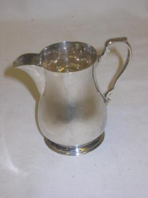 Appraisal: A CREAM JUG of baluster form with double scroll loop