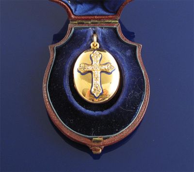 Appraisal: A gold oval locket pendant with diamond set cross in