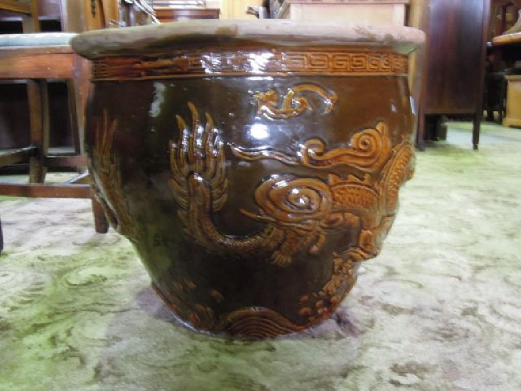 Appraisal: A Chinese earthenware jardini re treacle glazed with trailing dragon