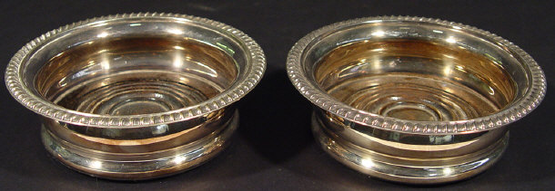 Appraisal: Pair of circular silver plated wine coasters with turned mahogany