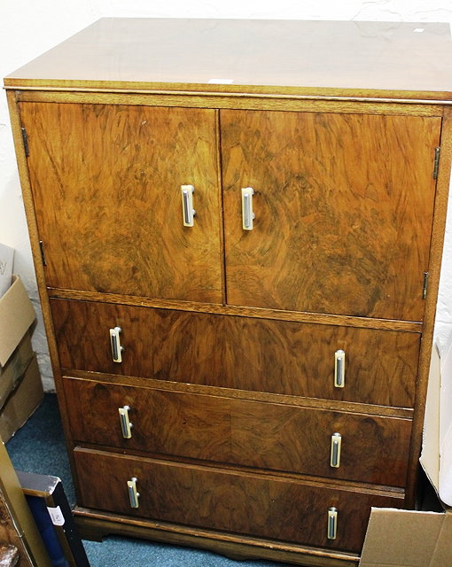 Appraisal: AN ART DECO WALNUT TALLBOY with cupboard section enclosing one