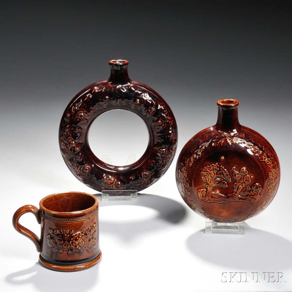 Appraisal: Three Rockingham-glazed Vessels a foliate relief-molded donut-shaped flask a flask