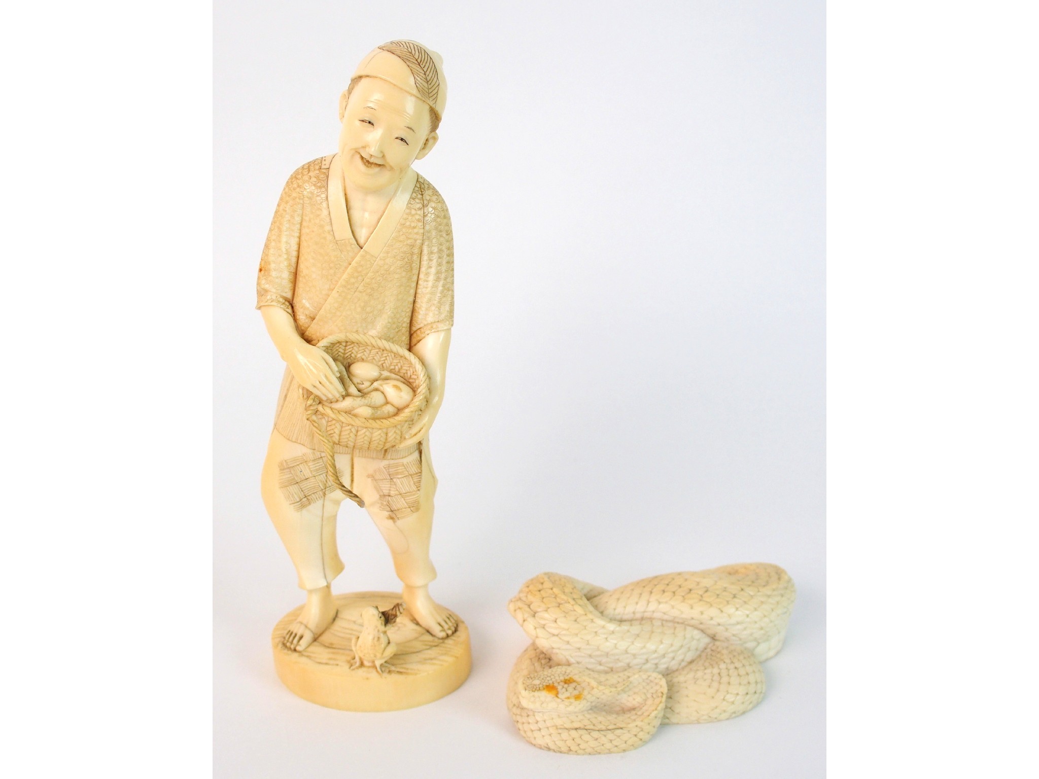 Appraisal: A Japanese ivory okimono of a manstanding and holding a