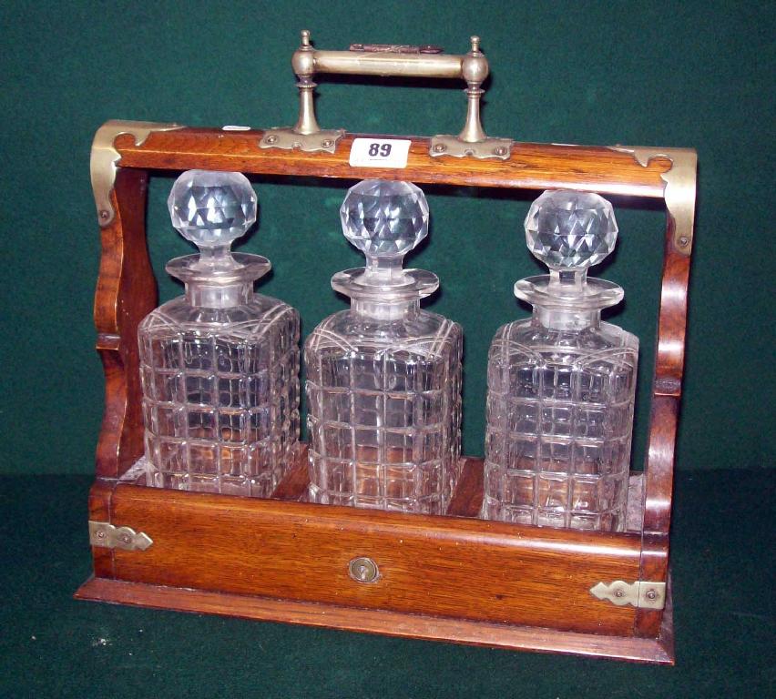 Appraisal: An Edwardian oak cased three bottle tantalus with plated mounts