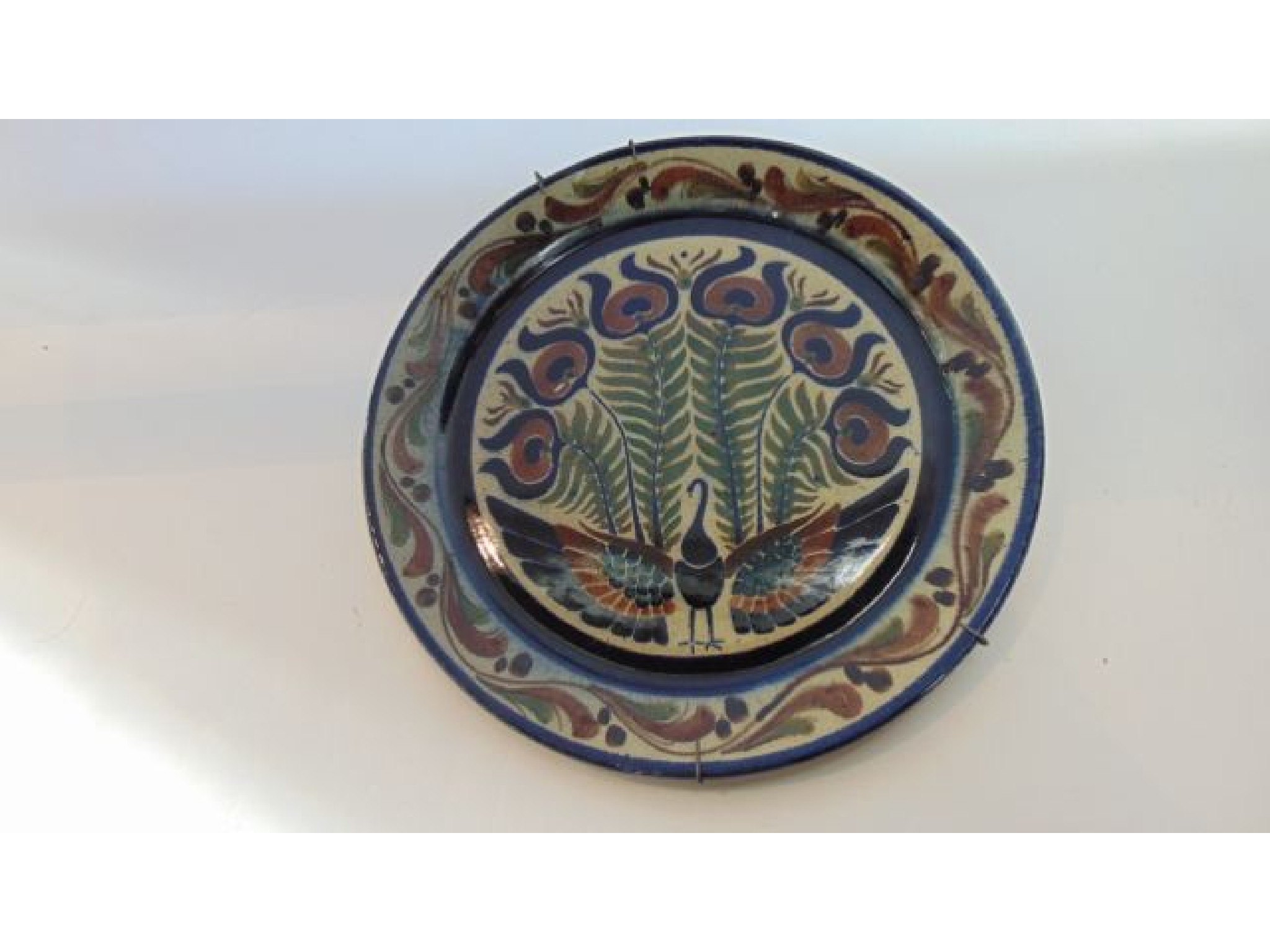 Appraisal: A Studio Pottery charger with painted stylised peacock decoration in