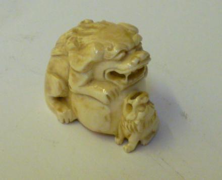 Appraisal: A JAPANESE IVORY NETSUKE carved as a Temple Lion beside