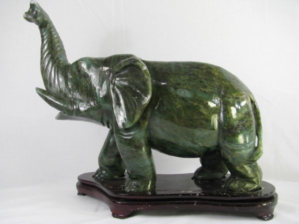 Appraisal: Dark green jade carved elephant walking with its trunk turned