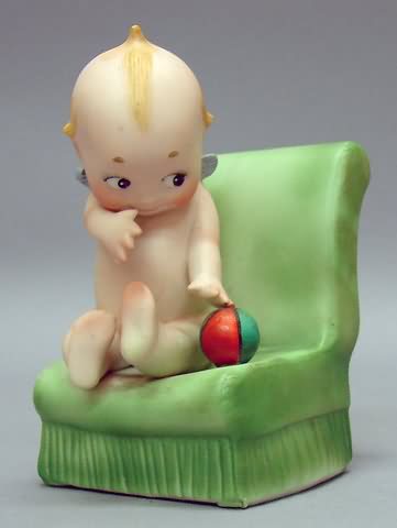 Appraisal: Kewpie sitting on green chair ball Bisque Kewpie is sitting