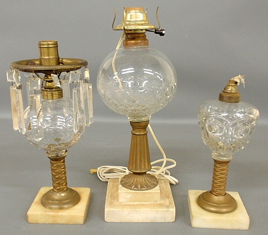 Appraisal: - Three oil lamps with clear glass fonts brass shafts