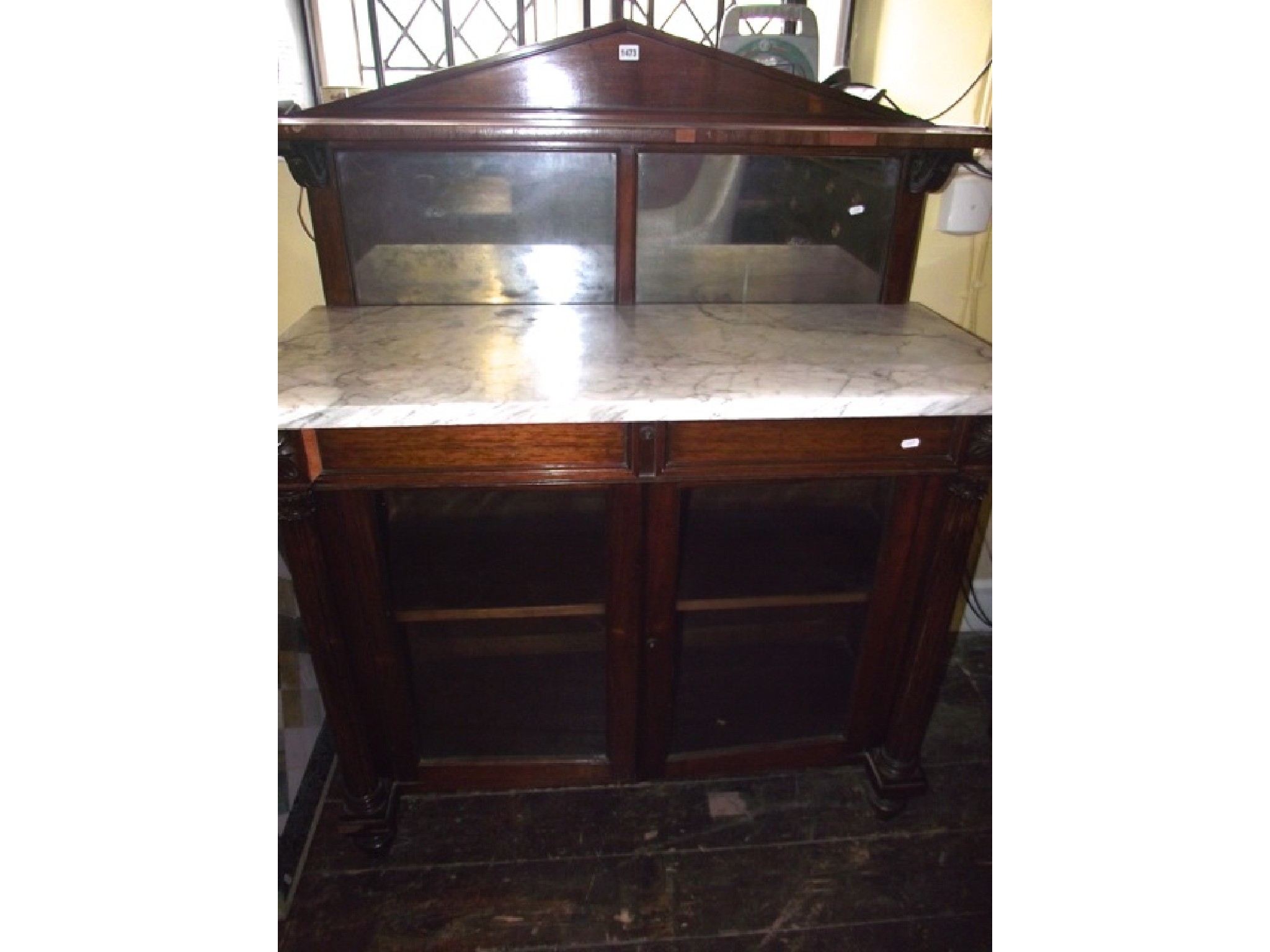 Appraisal: A Regency rosewood chiffonier with reeded column supports enclosing two