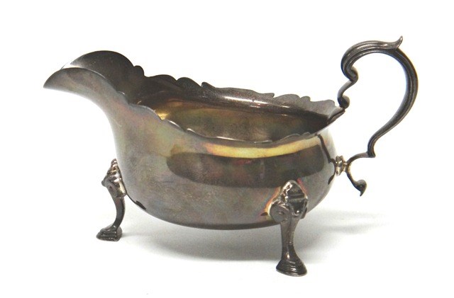 Appraisal: A silver sauceboat with a shaped rim scrolling handle and