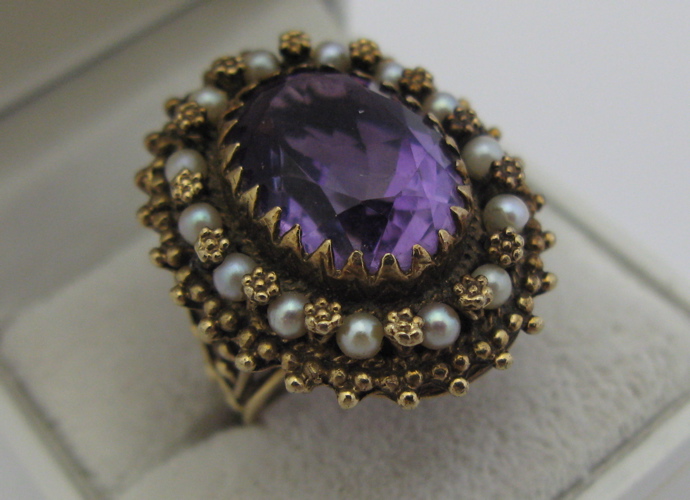 Appraisal: AMETHYST SEED PEARL AND K GOLD RING centering an oval-cut