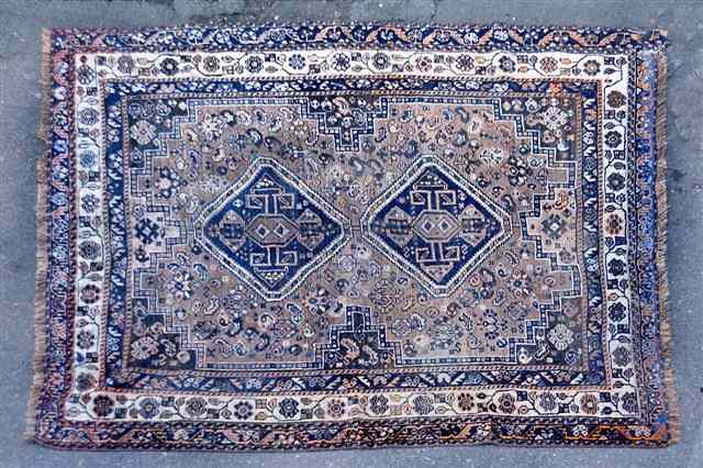 Appraisal: AN OLD PERSIAN SHIRAZ RUG decorated blue geometric medallions on