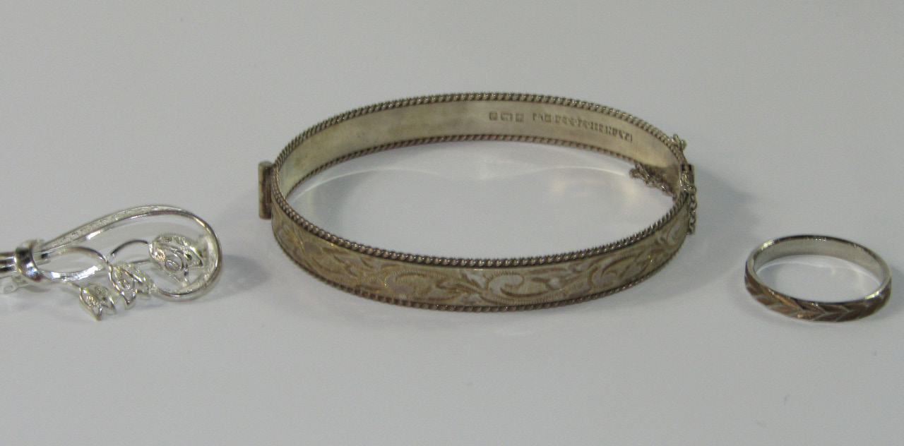 Appraisal: A silver hinged bangle a white metal wedding band and