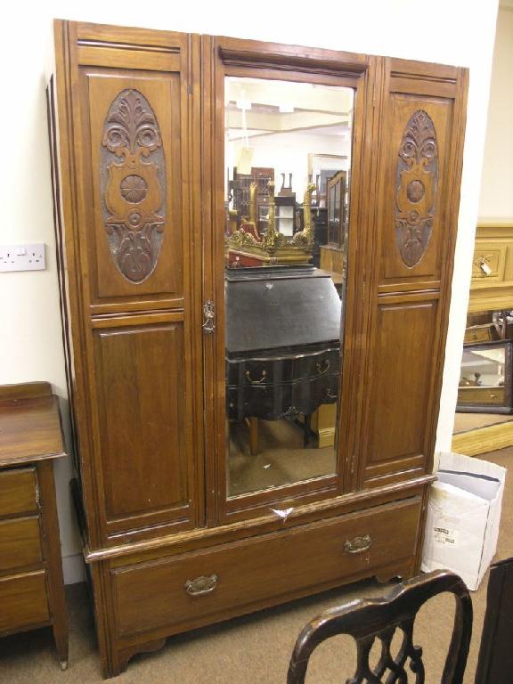 Appraisal: An Edwardian solid walnut wardrobe enclosed by three-quarter length bevelled