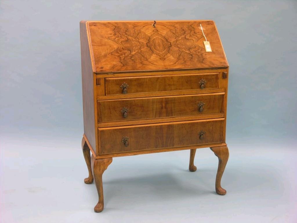 Appraisal: A walnut veneered bureau enclosed fittings above three long drawers