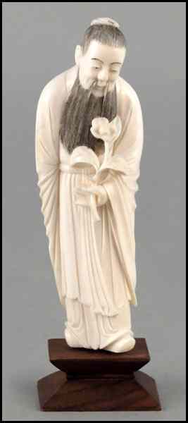 Appraisal: CARVED IVORY FIGURE HOLDING A FLOWER Raised on a ''