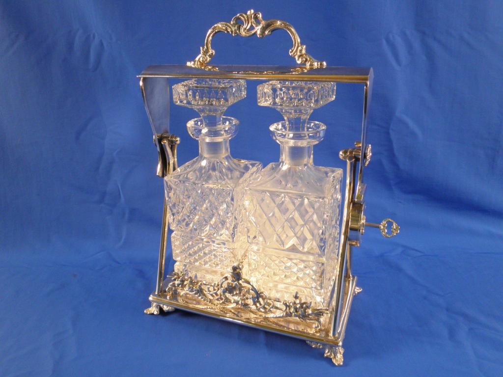 Appraisal: A silver plated tantalus with a scroll cast handle on