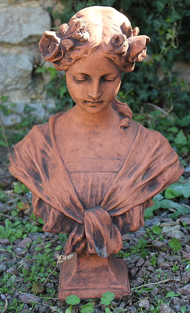 Appraisal: A TERRACOTTA COLOURED BUST OF A YOUNG GIRL with flowers