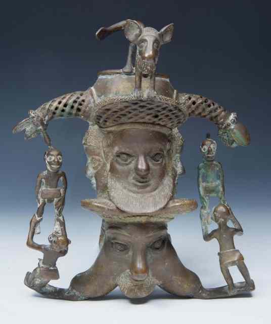 Appraisal: A CAST ETHNIC FIGURE showing masks and swinging figures surmounted