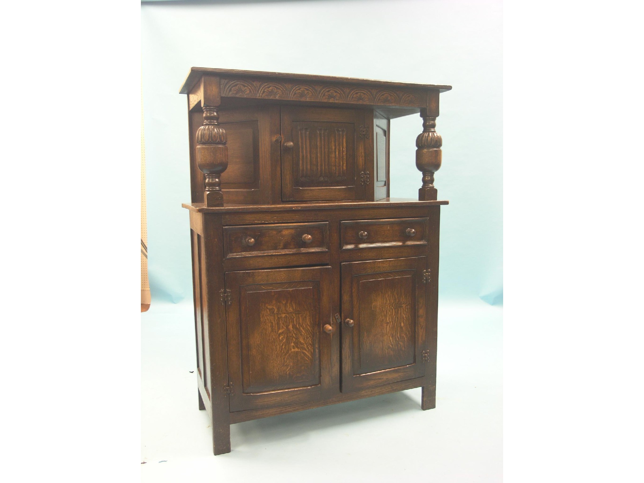 Appraisal: A solid dark oak court cupboard linenfold cupboard above panelled