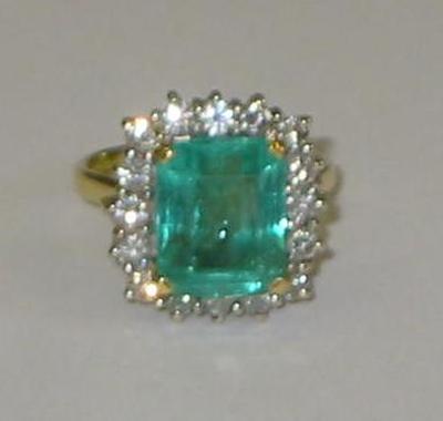 Appraisal: AN EMERALD AND DIAMOND RING the central trapp cut emerald