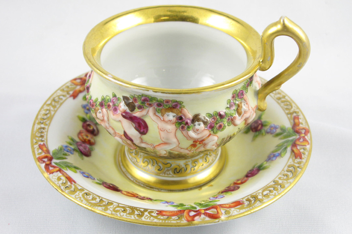 Appraisal: A CAPODIMONTE PORCELAIN TEA CUP AND SAUCER SET having raised