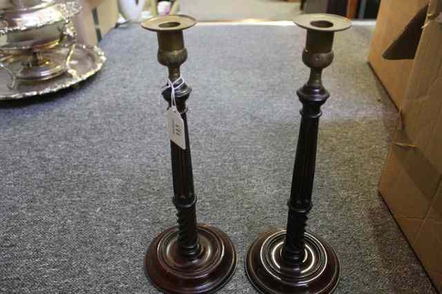 Appraisal: A PAIR OF MAHOGANY CANDLESTICKS with brass sconces each having