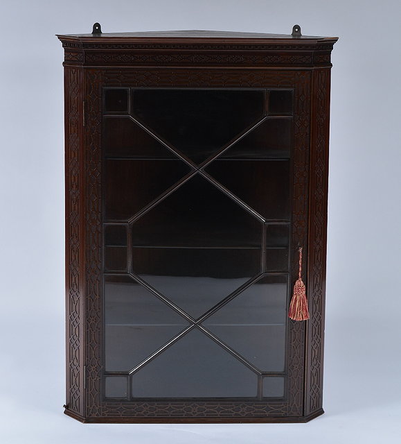 Appraisal: An Edwardian mahogany corner cupboardwith blind fret decoration fitted shelves