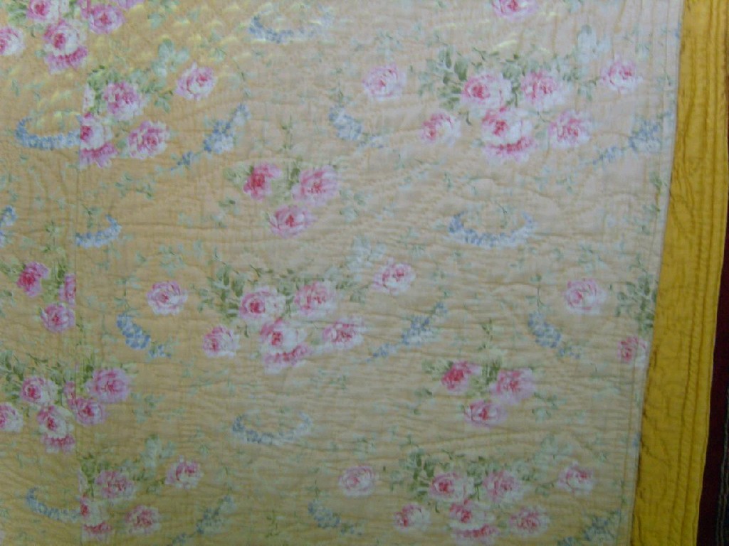 Appraisal: A yellow ground quilted bed cover with pink rose and