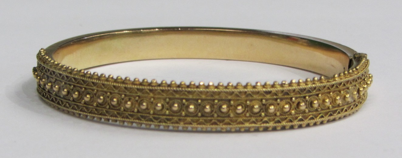 Appraisal: A gold oval hinged bangle the front with applied bead