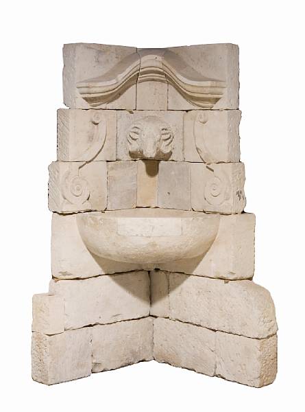 Appraisal: A Baroque style carved stone corner wall fountain The arched