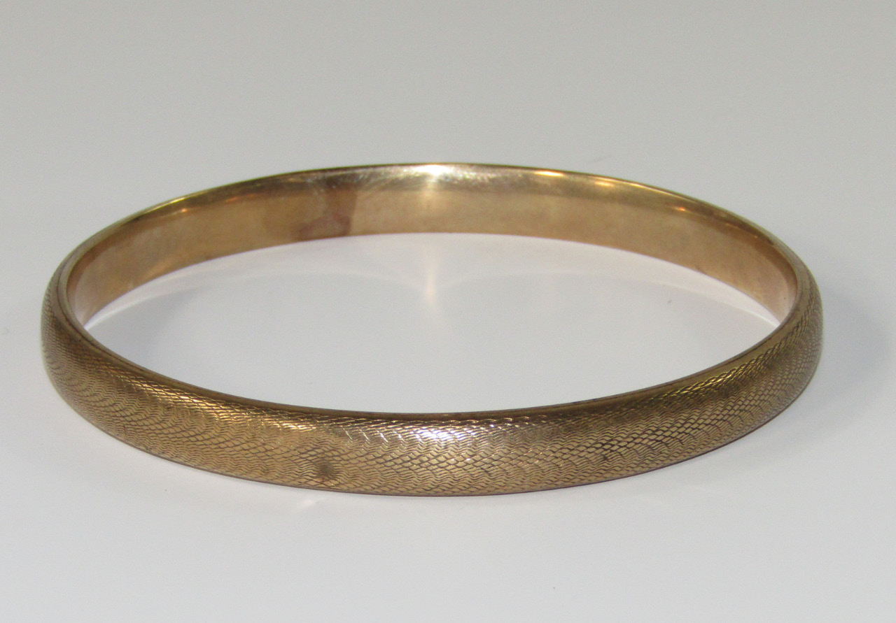 Appraisal: A ct gold bangle with engine turned decoration g