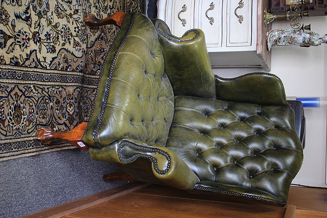 Appraisal: A GREEN LEATHER BUTTON UPHOLSTERED WING BACK ARMCHAIR with a