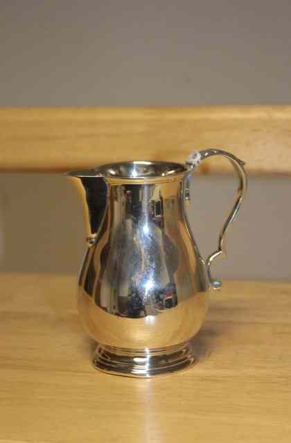 Appraisal: A SILVER CREAM JUG of baluster form with looping scroll