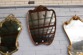 Appraisal: A shield shaped wall mirror in oak with carved pediment