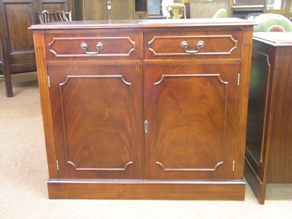 Appraisal: A modern reproduction mahogany cupboard flame-veneered top above a pair