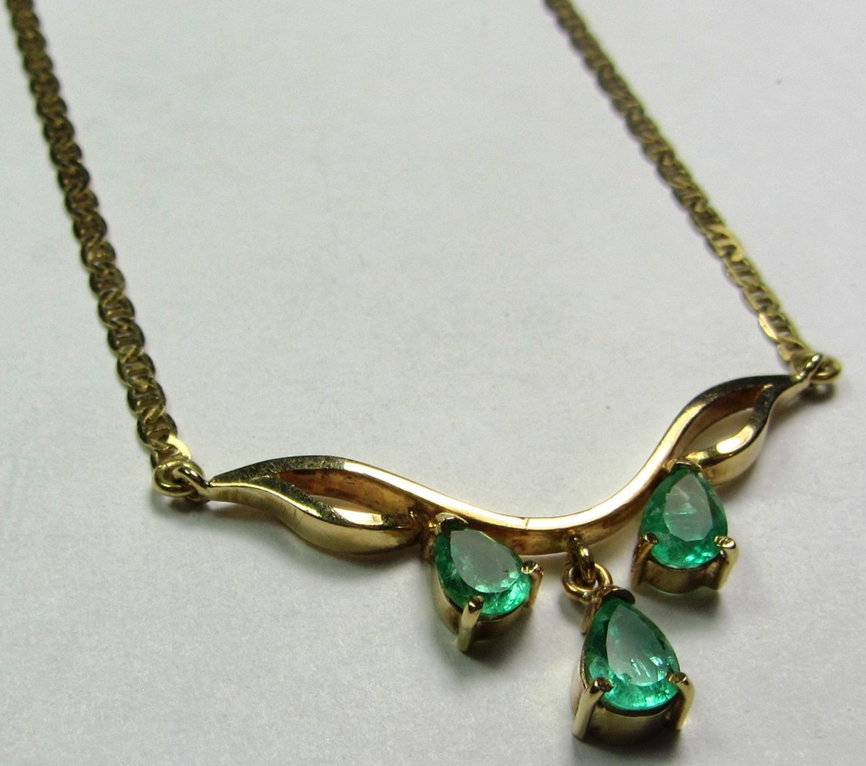 Appraisal: A gold and emerald set three stone necklace the front