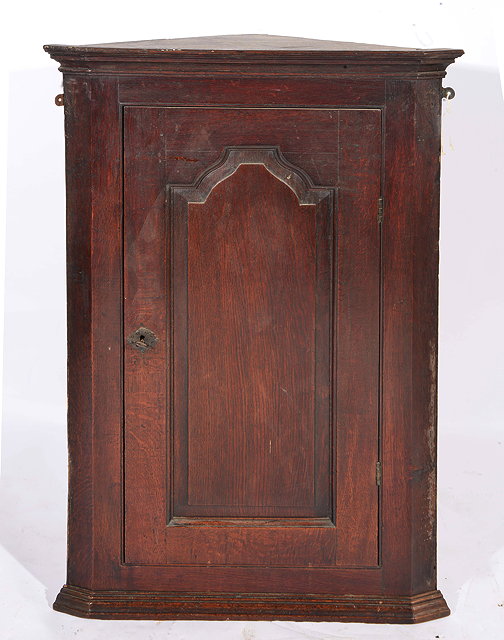 Appraisal: A GEORGIAN OAK HANGING CORNER CUPBOARD with panelled door enclosing