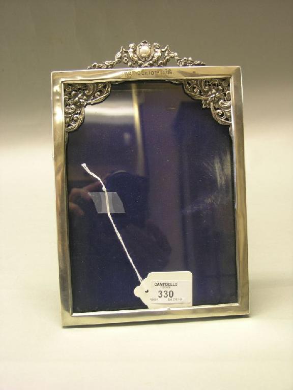 Appraisal: A silver photograph frame with embossed cherub cresting and floral